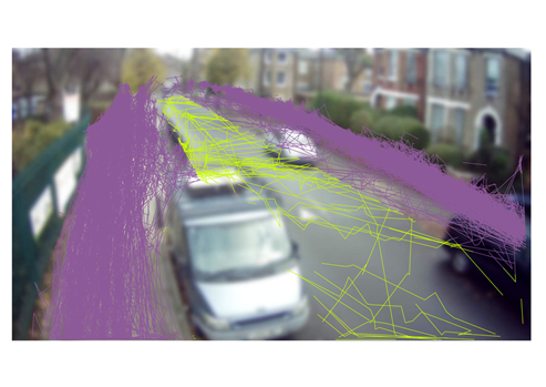 A photo of a street with superimposed pedestrian movements as purple and yellow lines (depending on whether they are in the footway or the carriageway). Most pedestrians are walking along the footway but there are also tracks crossing the carriageway or walking down it.