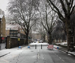 A road closed with bollards and a sign in the snow.
