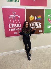 A young women stood in front of posters celebrating different sexualities.
