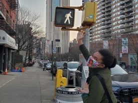 Photo of Ashundria Oliver pointing up at a street sign for 'Oliver St'