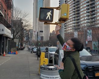 Photo of Ashundria Oliver pointing up at a street sign for 'Oliver St'