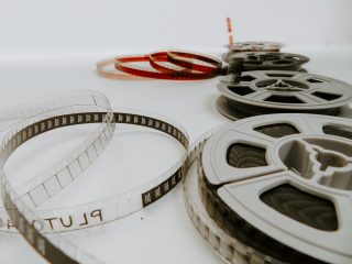 Film reels lined up away from the camera with the one closest in shot slightly unraveled to expose some of the film reel