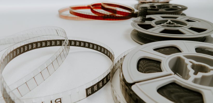 Film reels lined up away from the camera with the one closest in shot slightly unraveled to expose some of the film reel