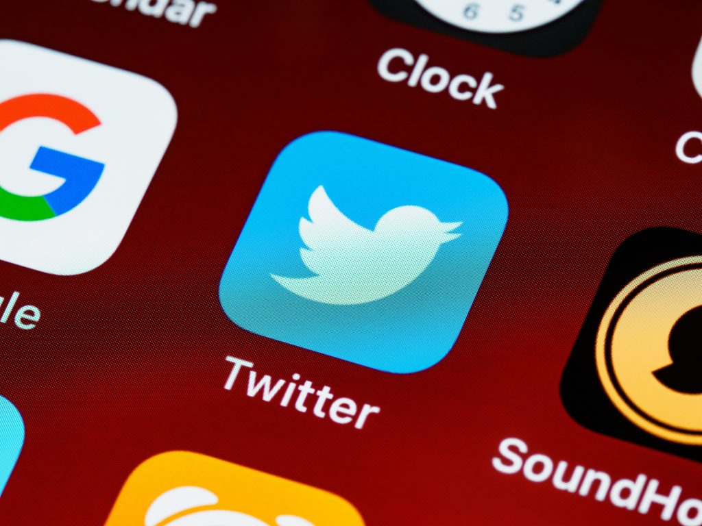 Twitter app icon is central on what appears to be a digital device and surrounded by other app icons.