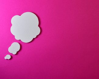 Pink background with three speech bubbles, enlarging in size in an upward trajectory, to the left of the shot