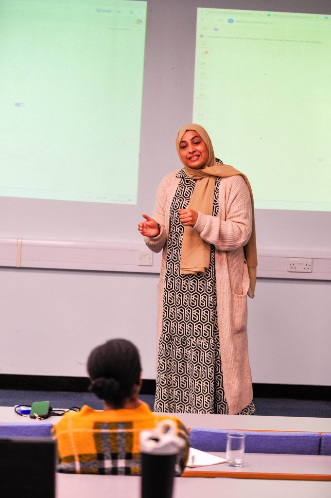 A presenter on the stage looking at a delegate on the front row.