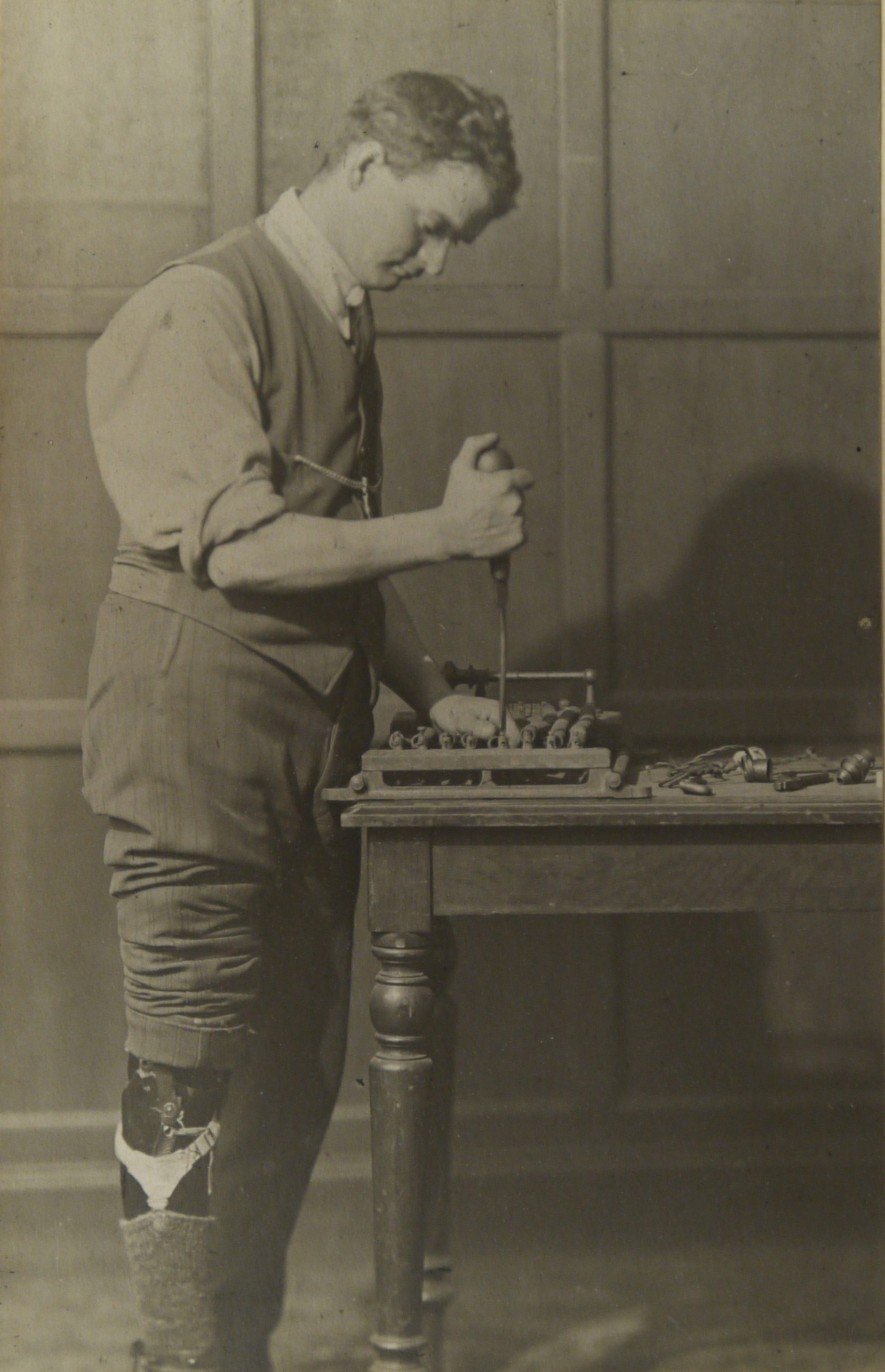 Ex-serviceman with a prosthetic leg doing electrical work at a table