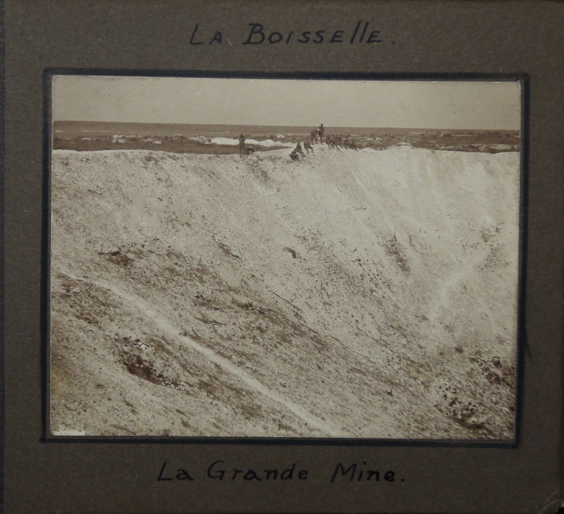 Photo of the Lochnagar mine crater in France, with men sitting round the rim