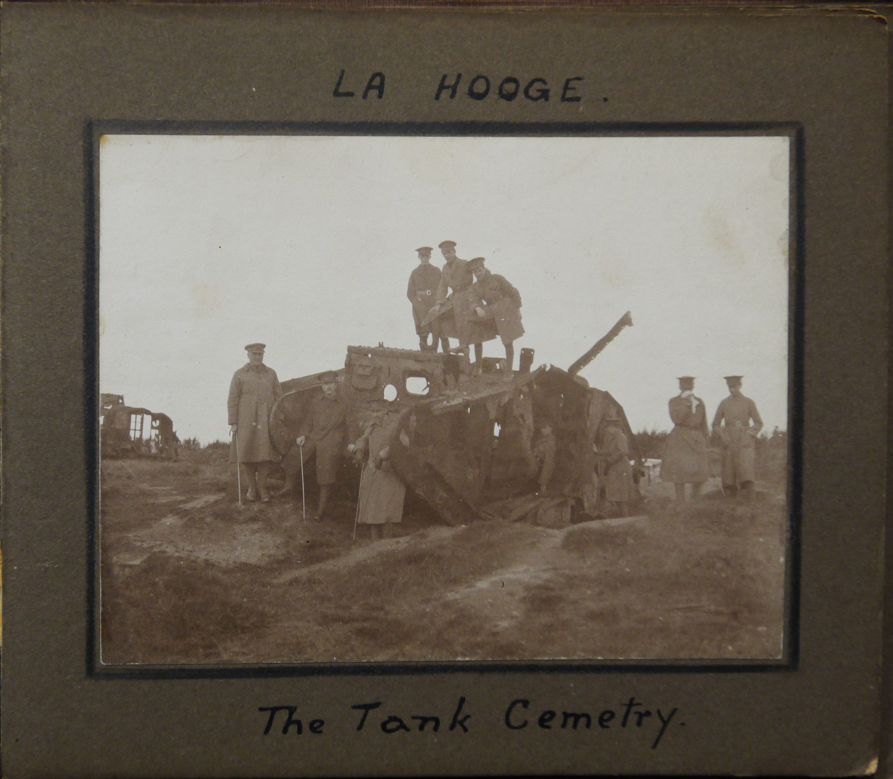 Photo of La Hooge tank cemetry with men standing on and next to a broken tank