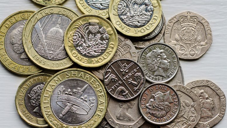 A pile of pound coins on a flat surface.