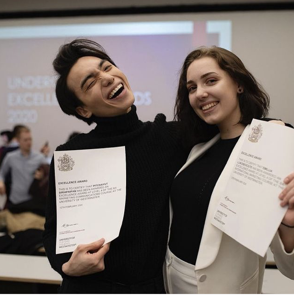 Peace and his friend Emily holding up their Undergraduate Excellence Award certificate