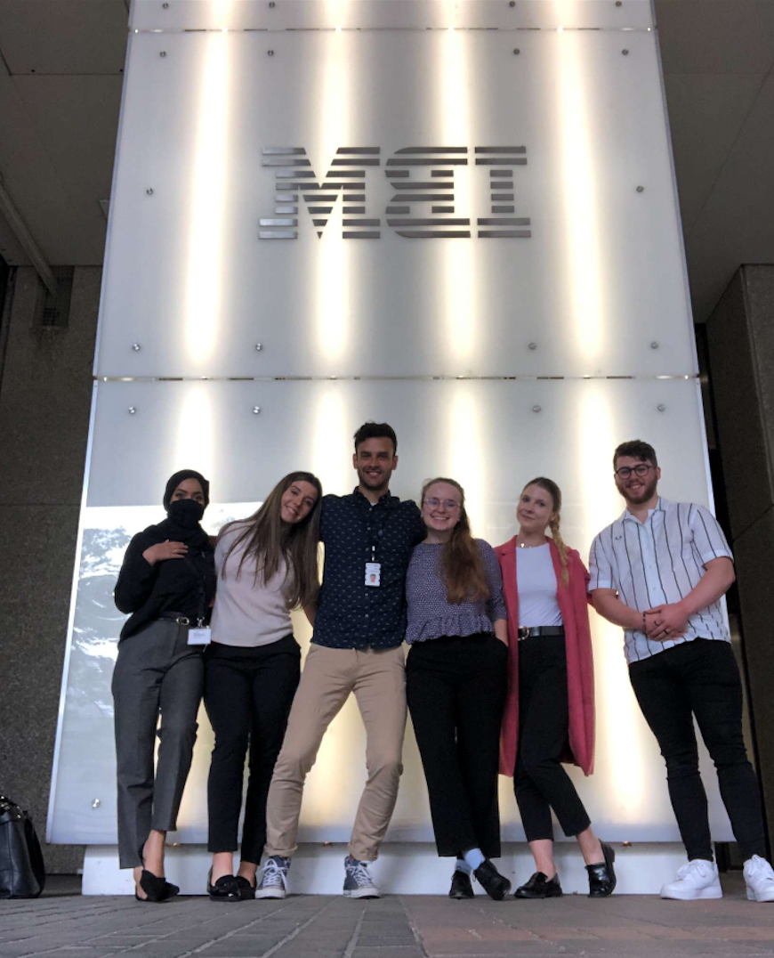 Juan Restrepo Flores poses with colleagues/coworkers in front of an IBM logo.