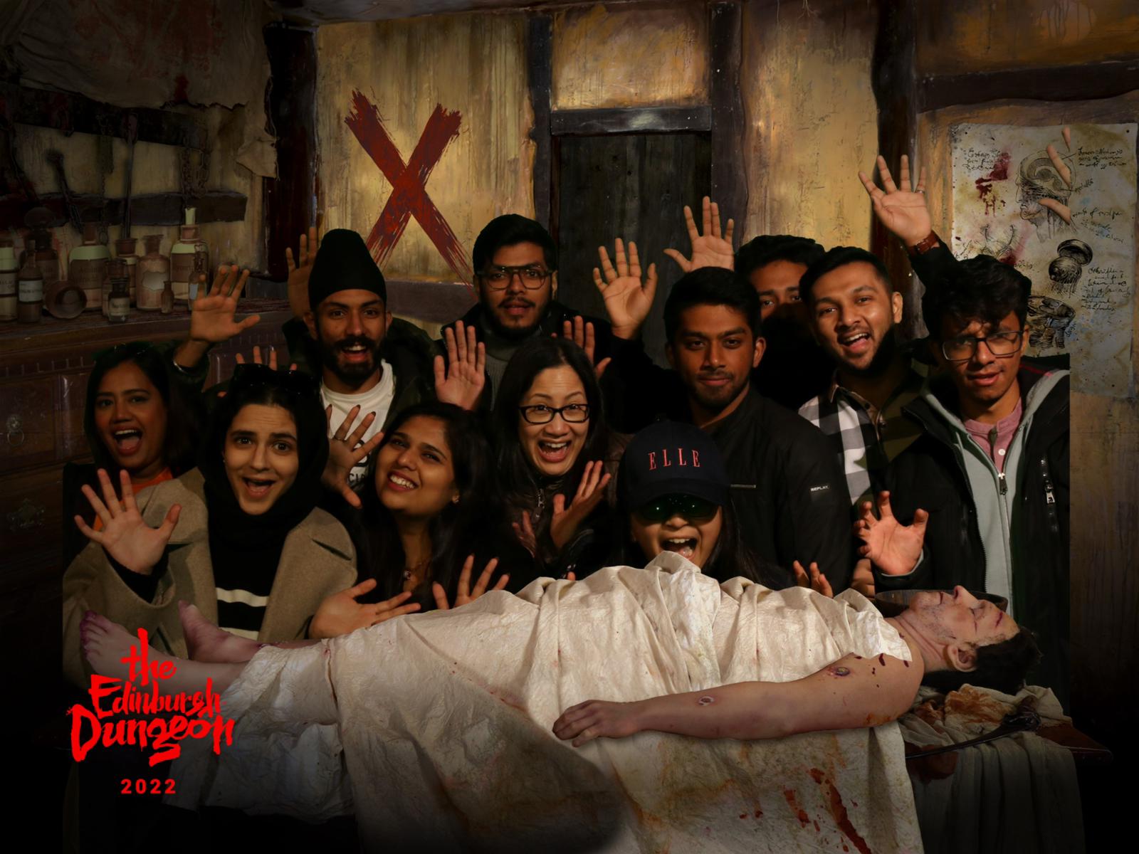 The Edinburgh Dungeon staff and students with mummy prop. Gruesome, horror. Souvernir photo with Edinburgh Dungeon logo.