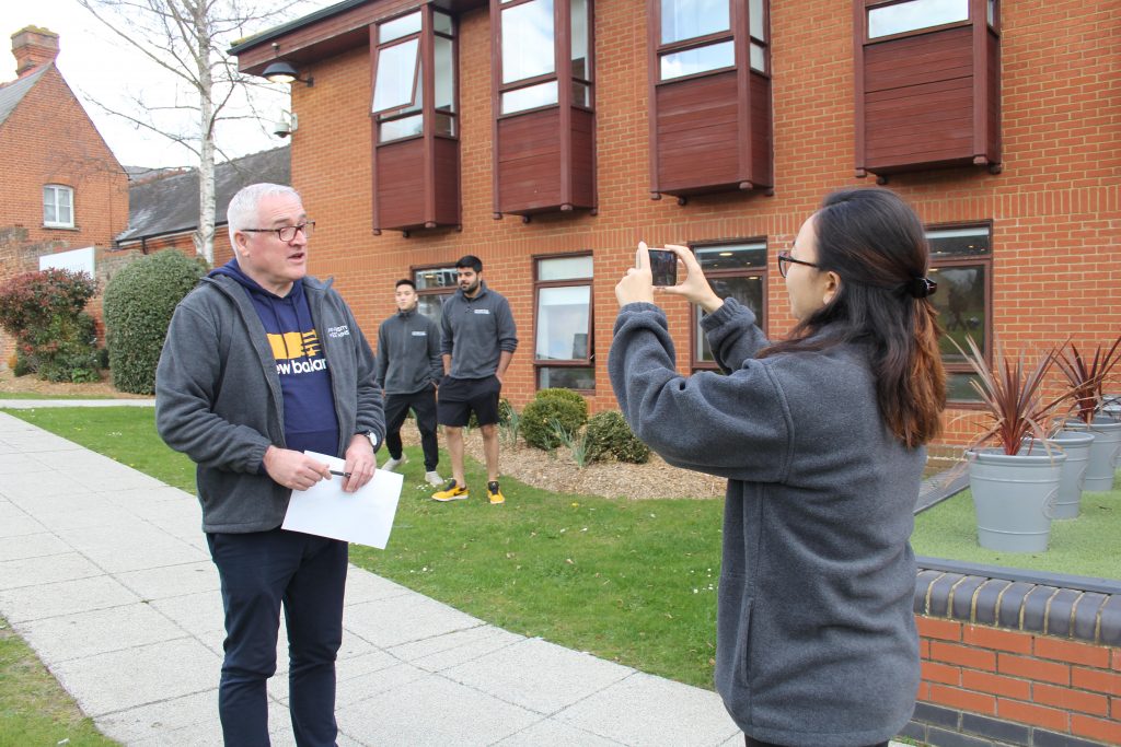 Lecturer, Kevin Hefferman being pictured by a student holding a smartphone on the grounds of the Beaumont Estate