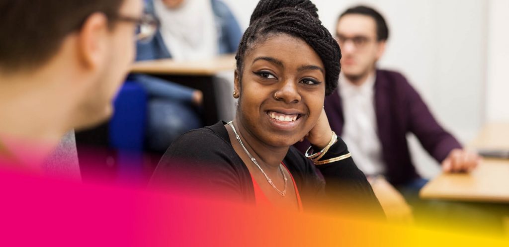 Female student smiling whilst talking to a male student