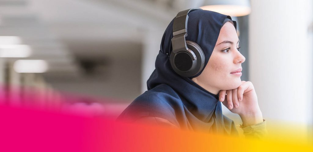 Female student wearing headphones whilst sitting at a computer