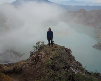 Photo of Michael at the top of a mountain in Java standing above a sulfuric lake