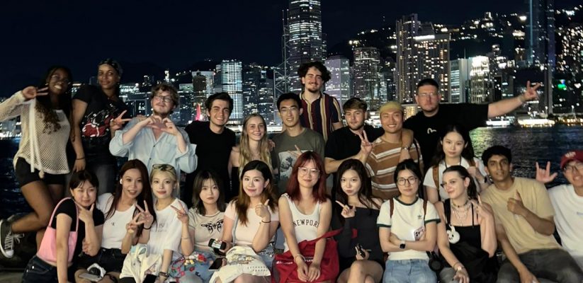 A group of people posing for a photograph in front of the Hong Kong skyline at night