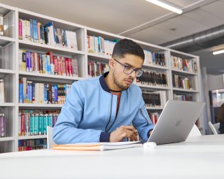 Student studying at laptop in library