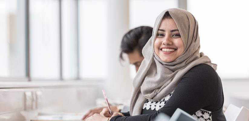 Girl smiling whilst writing in a notebook