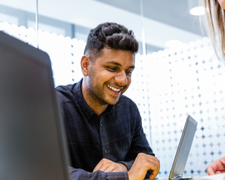 Male student smiling and working at laptop