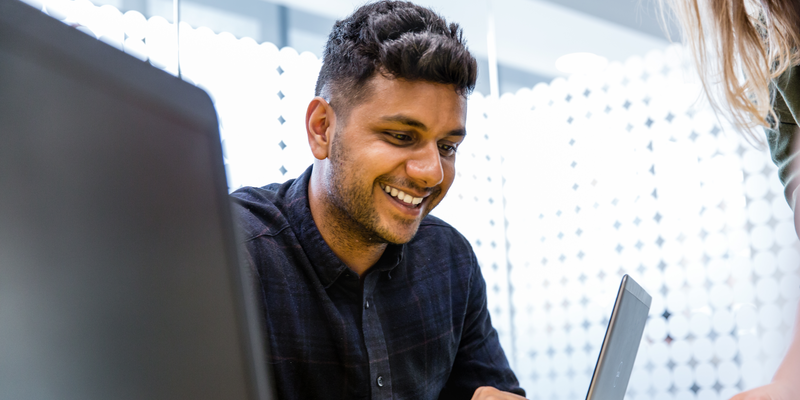 Male student smiling and working at laptop