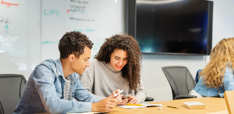 Two students sat at a table making notes about their lecture