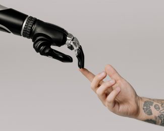 Image shows a robotic hand connecting with a human hand
