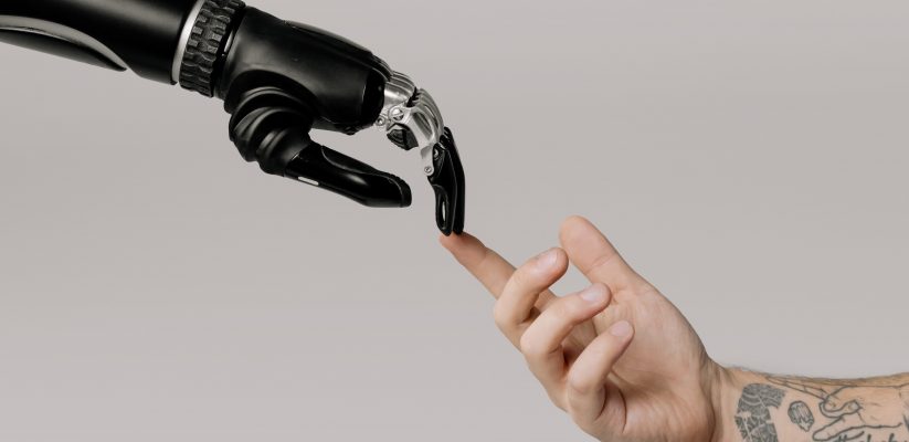 Image shows a robotic hand connecting with a human hand